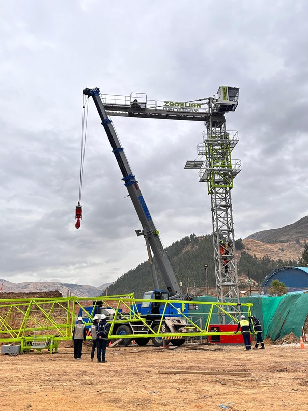 Grúa telescópica junto al mástil de una grúa torre en Calca