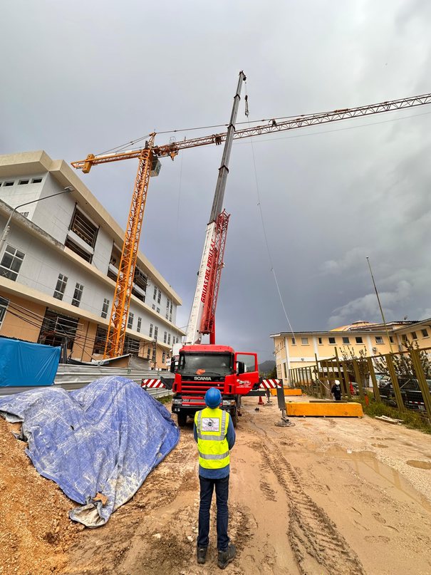 Supervisor de obra frente a una grúa telescópica y una grúa torre