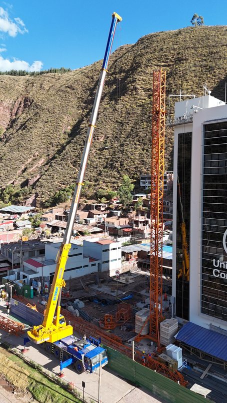 Grúa telescópica amarilla trabajando junto a un edificio en Oropesa, Cusco